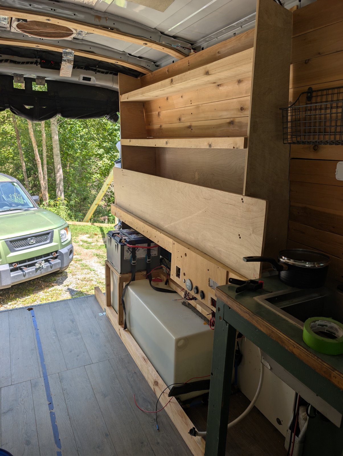 Upper shelving along the wall, with the battery and water tank below and the rear doors open